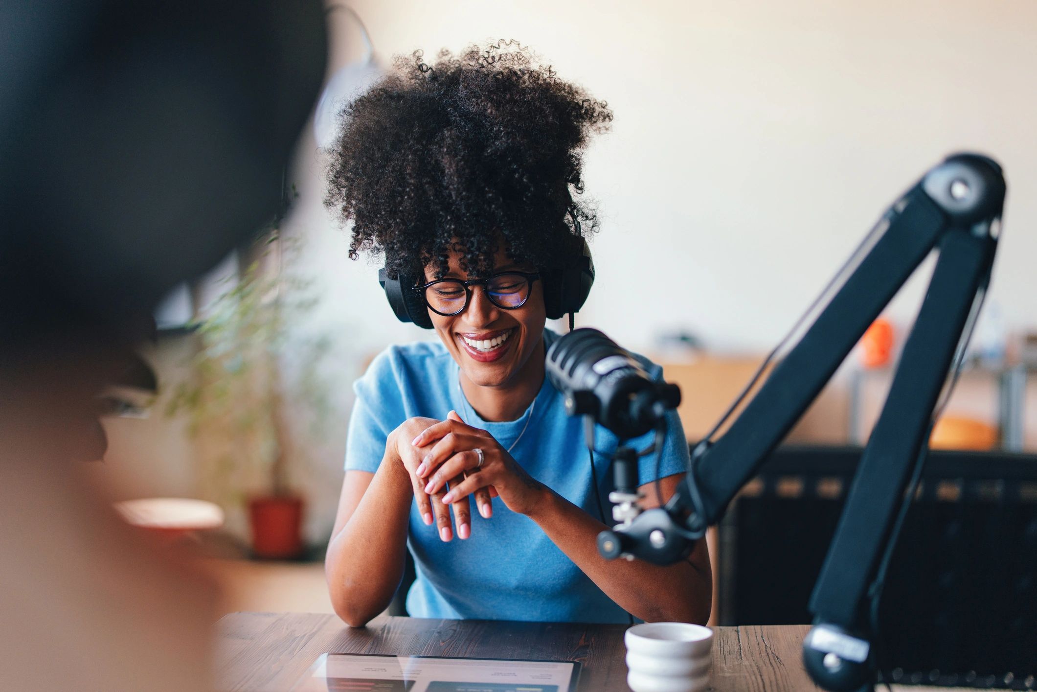 Podcast host speaking into a professional microphone in a modern studio